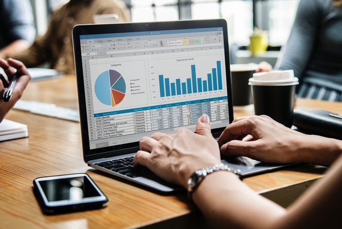 Image of person typing on laptop with chart on screen