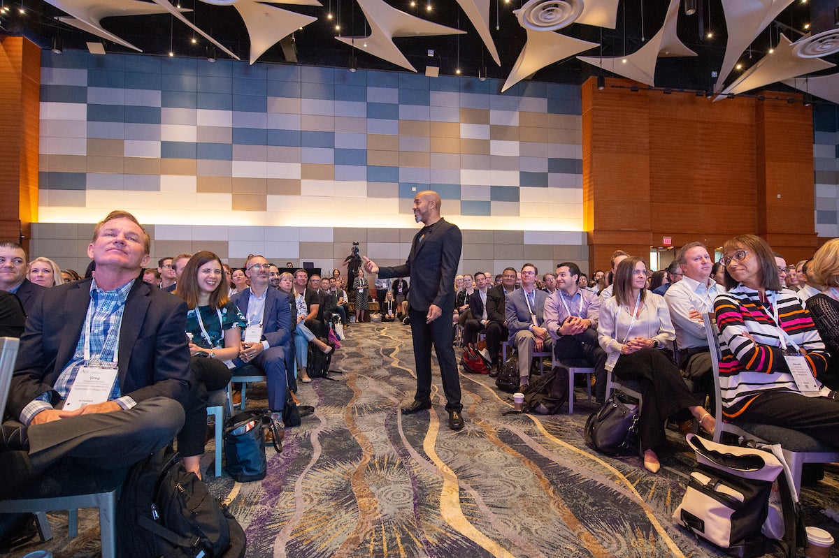 Trevor Faure walks among crowd at the annual meeting opening session