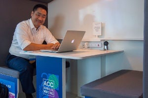 ACC member at desk with laptop.