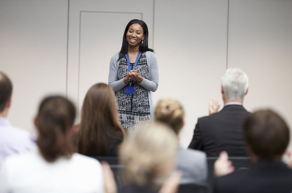 Woman in a blue suit lecturing to a crowd