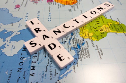 Scrabble letters on a map spelling Trade Sanctions