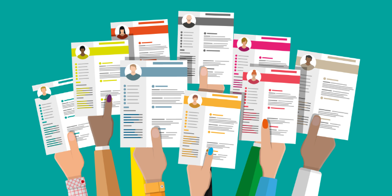 a diverse group of hands holding out resumes