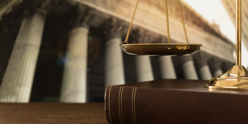 a book and scales of justice in front of a court room