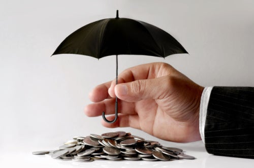 image of a suited hand holding a tiny umbrella over coins