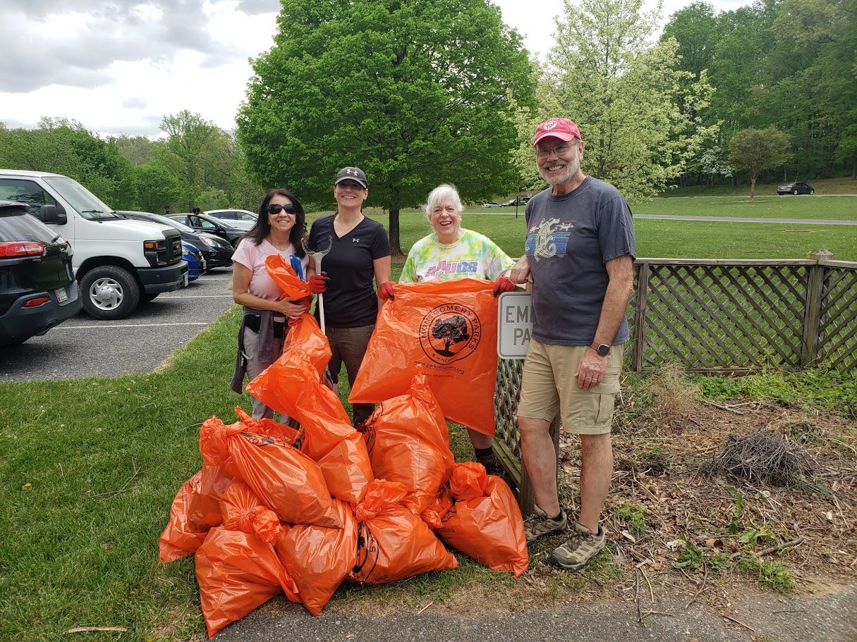 People outside holding trash bags 